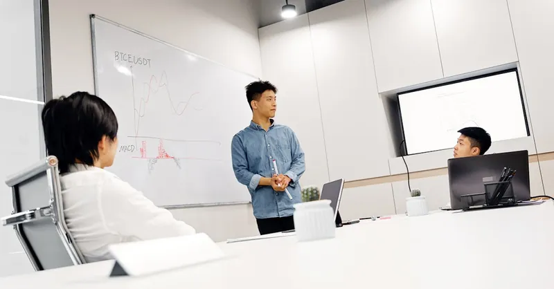 Professional business meeting with presentation and data analytics on whiteboard.