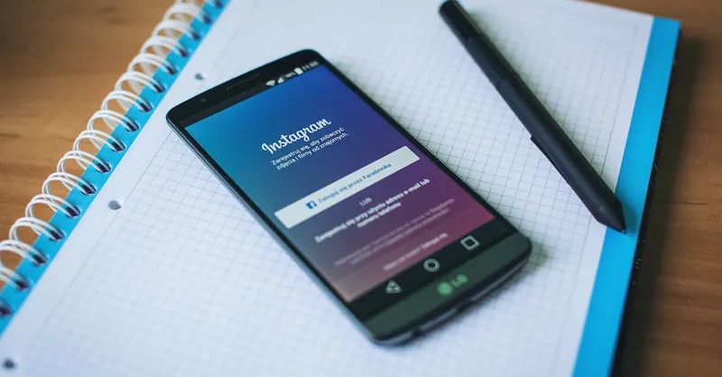 A smartphone displaying Instagram on a notepad with a pen, symbolizing social media and productivity.