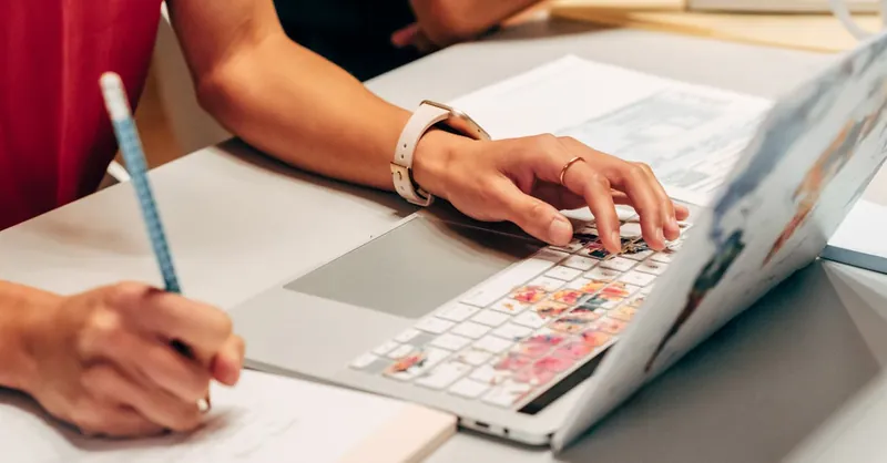 Woman writing notes and using laptop in a modern office setting. Interior workspace scene.