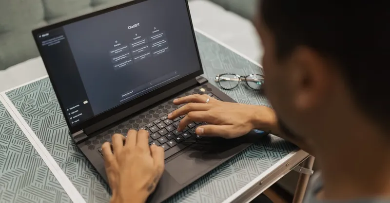 A person using a laptop to interact with AI technology indoors during the day.