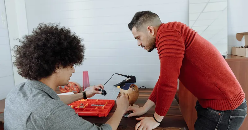 Two men collaborate on a creative project at a workshop desk, enhancing productivity and teamwork.