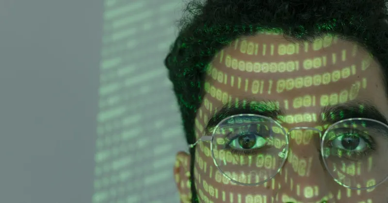 Close-up of a man with binary code projected on his face, symbolizing cybersecurity.