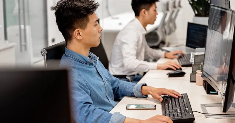 Young professionals working on computers in a modern office environment, focused on their tasks.