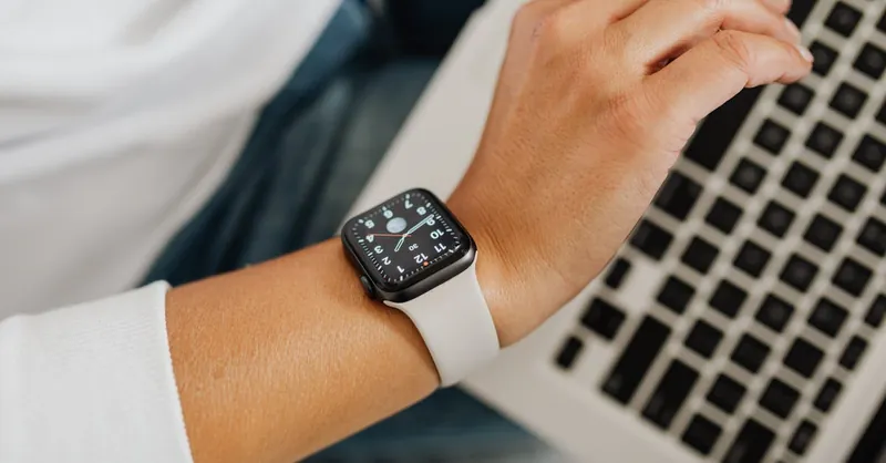 A person wearing a smartwatch working on a laptop, showcasing modern technology integration.