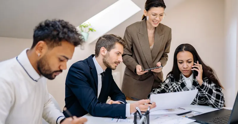 Group of professionals collaborating in a bright, modern office environment with digital devices.