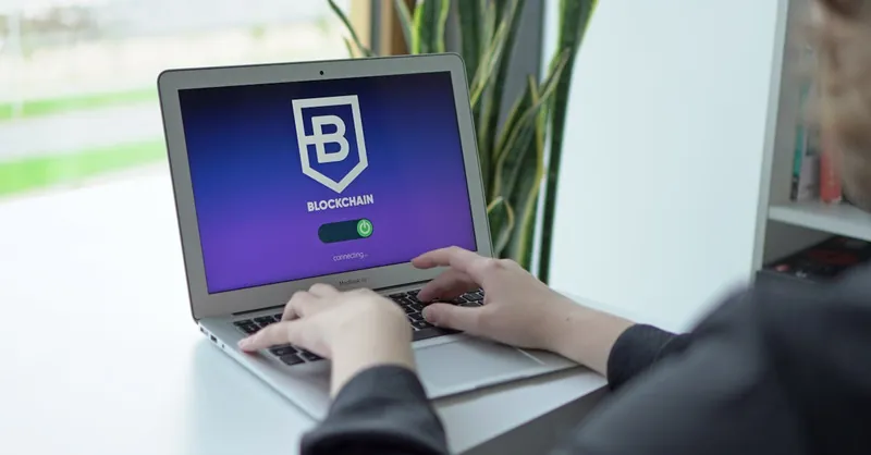 Close-up of hands on a laptop displaying a blockchain application, showcasing modern technology.