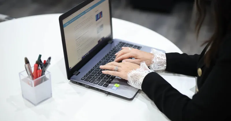 A woman typing on a laptop in a contemporary office setting, showcasing technology and efficiency.