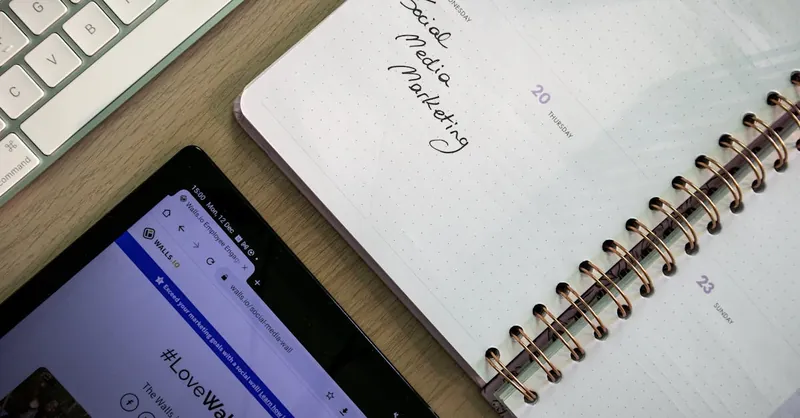 Top view of a notebook, tablet, and keyboard used for social media marketing planning.