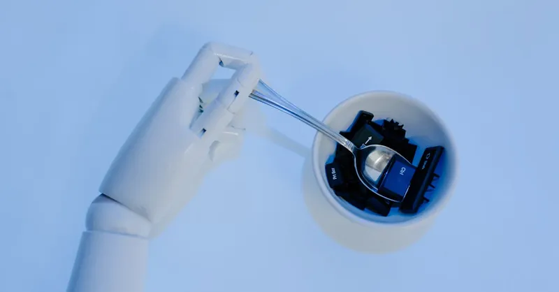 A robotic hand holds a spoon filled with keyboard keys, symbolizing AI and technology fusion.