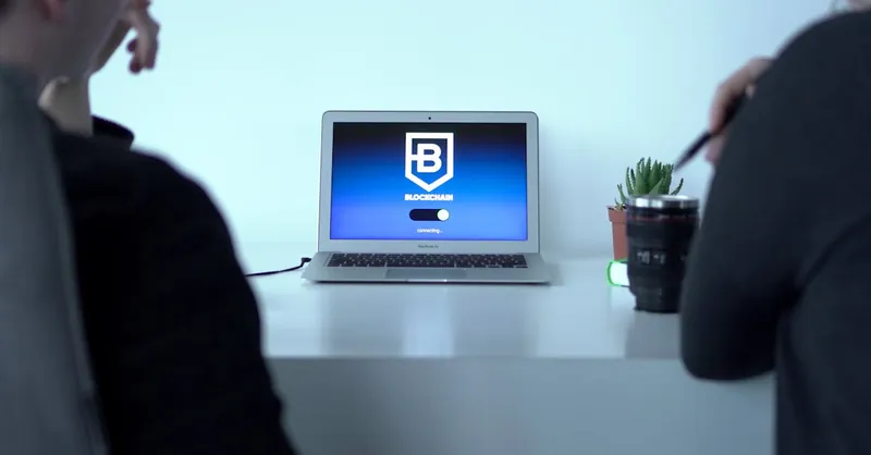 Colleagues discussing blockchain technology with a laptop in a modern office setting.