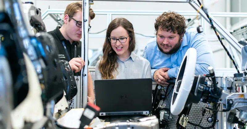 Engineers collaborating on a car project in a modern automotive workshop using advanced technology.