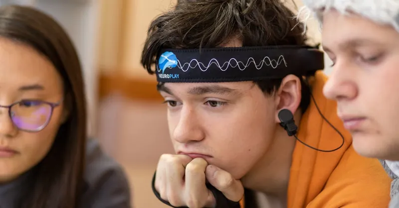Teenagers engaged in a study session using a neurotech headband for focus and concentration.