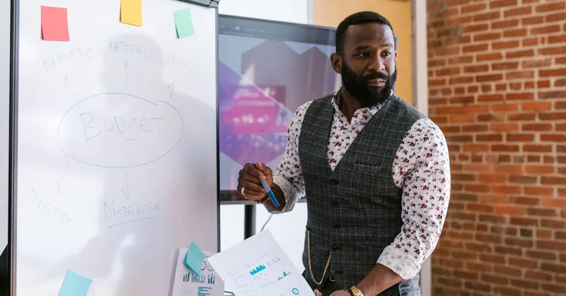 Entrepreneur presenting budget strategy using whiteboard in modern office.