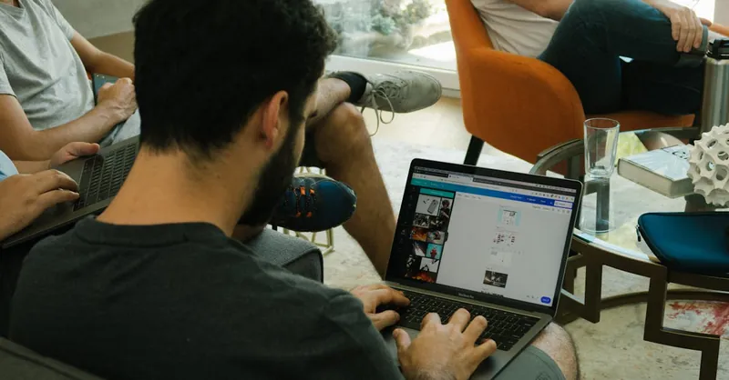 Three adults engage in digital collaboration with laptops in a modern office.